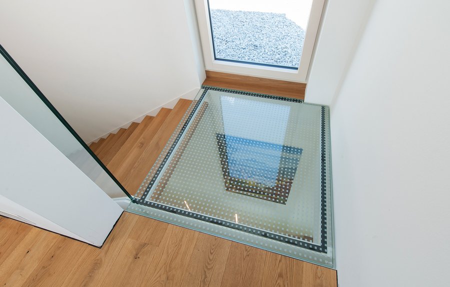 Die Bodenverglasung am Treppenaustritt ist ein interessantes Detail und bringt als Blickfang viel Tageslicht in den darunterliegenden Bereich. Au&#223;erdem verbindet sie auf geschickte Weise die Holztreppe mit dem Holzboden des Wohnraumes.